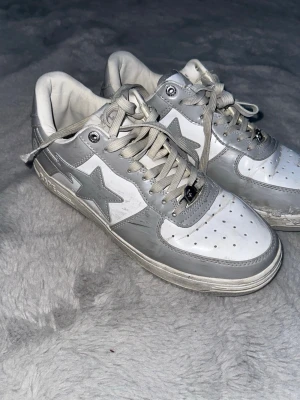 Bape skor (inte bra skick) - Grå vita bape skor, size 43, inte de bästa skicket. Ganska stort håll på framsidan av en av skorna