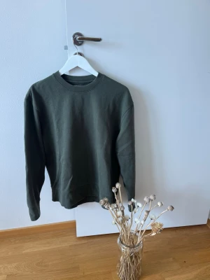 Olivgrön sweatshirt från Topman - En stilren olivgrön sweatshirt från Topman med rund halsringning och ribbade muddar vid ärmslut och nederkant. Perfekt basplagg i mjukt material som passar till det mesta. Enkel och clean design utan tryck eller mönster.