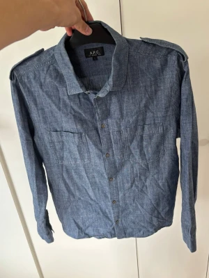 Otrolig APC Jeanskjorta L - En väldigt snygg unik och eftertraktad APC Jeanskjorta i storlek L säljes. Grym passform och inga hål eller fläckar i utmärkt toppskick! Super snygg på och perfekt för alla tillfällen nu till sommaren. Nypris på flera tusen tveka inte vid minsta fundering!