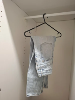 Ljusblå raka jeans i denim - Säljer ett par ljusblå jeans i klassisk rak modell från HM i storlek 146. Jeansen har fem fickor och är tillverkade i denim med en vintagekänsla. Perfekta för en avslappnad och trendig stil. 