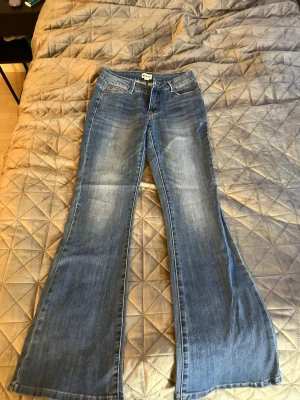 Blå bootcut jeans från Madlady - Säljer ett par blå jeans från Madlady i modellen bootcut.. Jeansen har klassisk femficksdesign, midrise midja och är i stretchigt denimtyg. Perfekta för dig som gillar retrostil och vill ha extra längd på benen.
