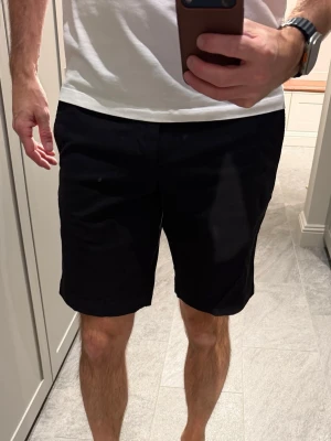 Svarta klassiska shorts - Stilrena svarta shorts. Klassisk design med bälteshällor och två bakfickor med knappar. Perfekta för sommaren och lätta att matcha med olika outfits.