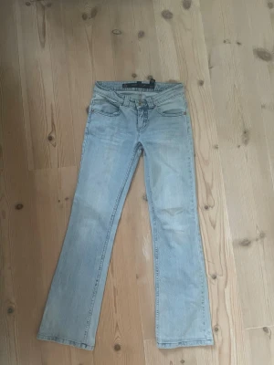 Ljusblå bootcut jeans  - Säljer ett par ljusblå bootcut jeans med låg midja. Jeansen har en snygg tvätt och utsvängda ben som går ut lite nertill. Perfekta för en avslappnad och trendig look. Dom var köpta på Karlaplan loppis för 500kr har använt dom en gång sen dess