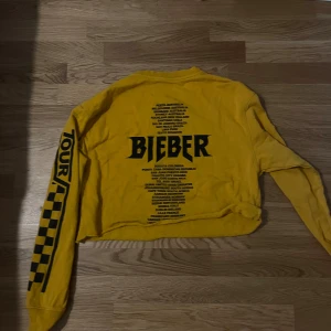 Gul tröja från Team Bieber - En gul långärmad tröja från Team Bieber med texten 'BIEBER' och turnédatum tryckt på baksidan. Framsidan har texten 'TOUR' och ett schackrutemönster. Ärmarna har också texten 'TOUR' och schackrutemönster. Vid köpa av flera varor sänks priset 🌟🌸