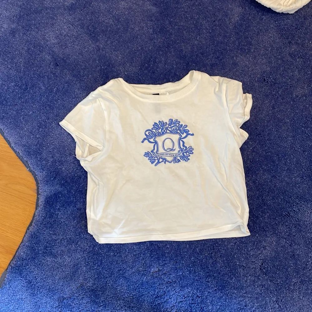 den har en blå bild och text på framsidan det står ”queen of your heart”.. T-paidat.
