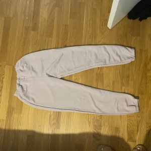 Ljuslila mjukisbyxor - Ett par bekväma ljus lila mjukisbyxor med elastisk midja och muddar vid bensluten. Byxorna har en lös passform och är perfekta för avslappnade tillfällen.