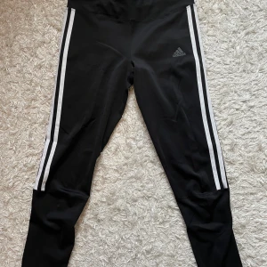 Adidas träningstights - Ett par oanvända träningstights från Adidas i nyskick. Byxorna är ankellånga och har knytsnöre  i midjan. 200kr + frakt