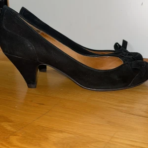 Klacksko i mocka - Strl 38, svart mocka med liten rosett rundad, något spetsig tå, ca 5 an klack. Bra skick
