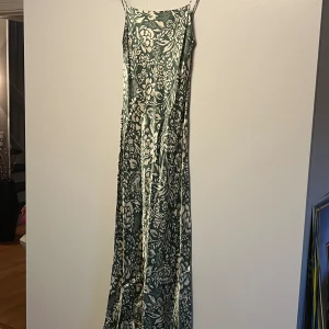 Grön midiklänning i siden - Ber om ursäkt för ljuset i dom dåliga bilderna, färgen gör sig därför inte riktigt rättvisa! Kan skicka bättre bilder i chatten💚Säljer iaf denna otroligt fina gröna klänning med ljusbeiga krusiduller i siden-immitation!🍀Storlek XS, sitter som XS.