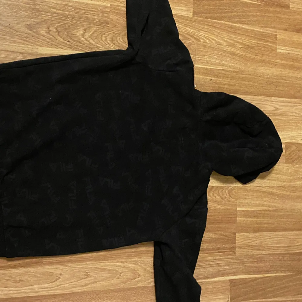 En svart FILA hoodie. Passar 13-15 åringar ( 13/14 är bäst rekommenderat). Hoodies.