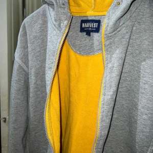 Grå hoodie med gul insida. - Grå tjock hoodie med gul insida från James Harvest Sportswear. Storlek XL. Jättefint skick.
