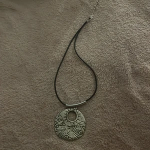 Halsband med silverberlock - Asballt halsband med peace märken på. Liknar runsten. Silver.