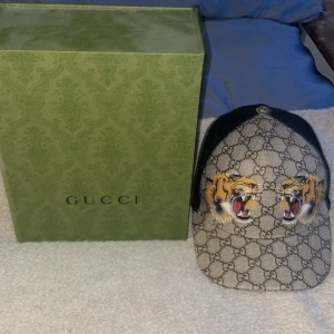 Gucci Keps  - Äkta guccikeps GG tiger ljus.  knappt använd 10/10 skick. Box medföljer!  OBS! vi står ej för frakten!