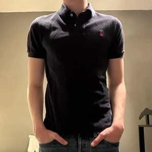 Polo Ralph Lauren - Skit snygg Raffe piké. Köpt på nk junior men storleken passar om du har xs och xs till s. Kvitto finns. Det är lite färg slitage kring kragen men annars är det 9/10 skick. Orginalpris 800kr hör av er vid frågor och pris kan diskuteras