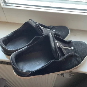 Arigatos storlek 41/42 - Ett par svarta arigatos med dragkedja. Skick 6/10 finns tecken på användning men har fortfarande mycket att ge. Bara att höra av sig vid frågor.