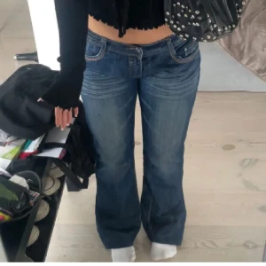 Lågmidjade jeans med detaljer  - Jättefina lågmidjade bootcut jeans med detaljer på baksidan, i bra skick. Säljs pga att de inte kommer tills användning. Kp för frågor! (Har justerbar knapp så man kan sätta den beroende på vad som passar en själv) 
