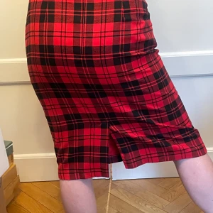 Läcker pennkjol - Westerlinds fodrad 80-talskjol i lättskött material. 40 grader fintvätt. Svart/rödrutig. Snygg passform, knappt använd! Litet sprund bak. 81 cm i midjan. 67 cm lång.