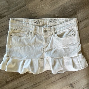 Vit volang jeanskjol - Köpt på plick, men var för stor för mig så säljer vidare. Det är waist 30 och måtten är 42 cm i midjan rak över och längden är 32 cm. Bara höra av er för fler frågor💗