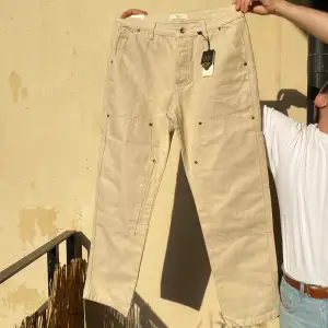 Carpenter Pants i Bone färg. Enbart testade alla lappar kvar. 16 oz 100% bomull canvas, slitstark workwear. Inköpt hos det brittiska klädmärket Pand & Co för 1300kr. Men tyvärr för små för mig :/ Har även ett likadant par svarta i min profil.