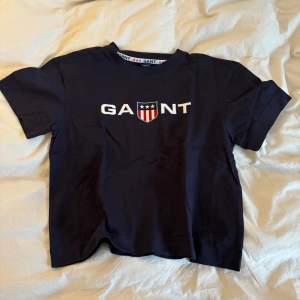 Säljer denna t-shirt från Gant, den är nästan använd eftersom att den aldrig kommit till användning och nu är för liten🫶🏻 Men den är i jättebra skick, inget som är trasigt, slitet eller någon fläck👌🏻köpte den från kidsbrandstore