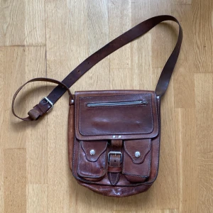 Vintage läderväska - En jättecharmig axelremsväska i tjockt läder med mycket utrymme!!  Remmen är justerbar och väskan ”stretchar” om du behöver få plats med mer prylar :)  Skickas helst! Skriv om du har frågor :)  