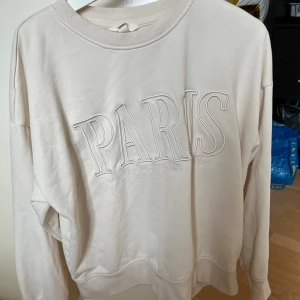 Vit tjocktröja - Vit tjocktröja som är köpt på H&M och är i storlek M. Använd mer än 2 händer fulla, syns inte att den är väl använd förutom på texten/trycket.