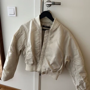 Kroppad bomberjacka beige - Kall beige bomberjacka som är kroppad i storlek XS. I nyskick. 