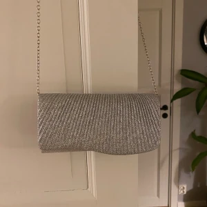 Glittrig väska  - Säljer denna glittriga väska, den passar perfekt som balväska då man kan lägga ner de långa bandet i väskan. Obs: glittrar av sig lite 