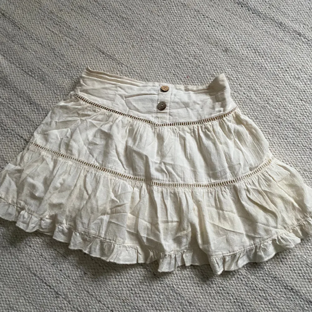Fin kjol från zara. Färgen är vit med en gulare ton och har bruna knappar. Perfekt sommar och standkjol. Inte använd mycket. . Kjolar.