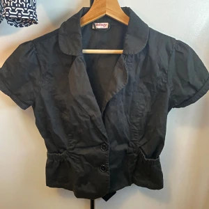 Kavajtopp - Så himla fin svart topp som tyvärr är lite stor för mig som är xs vanligtvis. Den är köpt second hand där det stod att det var stl xs-s men den är ganska stor vid bysten. Man kan dock knäppa igen den mer med en säkerhetsnål🥰kan skicka mått om så önskas!