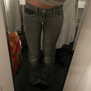 lågmidjade jeans - dom ör gråa med detaljer på bakfickorna