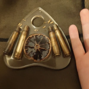 Stor ouijaplanchette i resin med apelsin och hylsor ouija - En stor planchette till stort ouijabräde eller som man kan hänga som dekoration på väggen. Med en torkad apelsin, hylsor i mässing och små guldflingor inuti