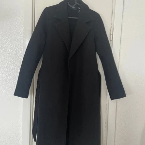 Svart kappa - Från Vero Moda i storlek XS. Köpt för ca 3 månader sen. Använd fåtal gånger och är i väldigt bra skick. Nypris 599kr. 