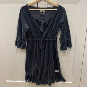 En jättefin velour klänning i en sorts mörkgrå/mörkblå, har lite spets uppe och nere och några fler små detaljer. 