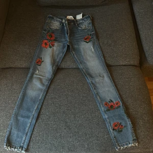 Zara jeans (blommönster)  - Storlek 34, använts en gång, så skick gott som ny, köpt i Spanien. Stil- skinnyjeans med röda blommor på. 