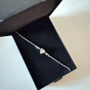 Silverarmband  - Armband i äkta silver med hjärtformad sten. Kan justeras och vara mellan 16-19 cm långt. Ser inget märke på det! OBS! Ingår ingen ”ordinarie” ask