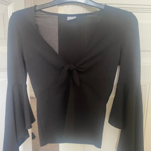 Tröja med knyt från ginatricot i storlek xs  - Tröja med knyt vid bröstet, armarna har volang, tröjan är i xs från ginatricot Knappt använd och är i fint skick 