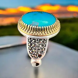 En vacker naturell turkos ring framkallar känslan av naturens skönhet och mystik. Ringen är smyckad med en äkta turkos sten, vars färg skiftar från djupblått till intensivt grönt, med naturliga ådror och inslag som ger varje sten en unik karaktär. 