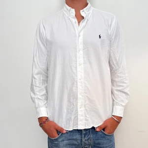 Ralph Lauren - Vit Ralph Lauren skjorta i storlek L. Skjortan är i fint skick men med ett lagat litet hål på armen (se bilden) Modellen är 186 cm lång. Orginalpris ca 1500 kr och nu endast 499. 