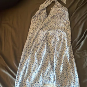 Vit klänning med blåa blommor på - Jätte fin sommar klänning, dock inte så lång hår ner till knäna typ. Lite svår vid dragkedja på sidan