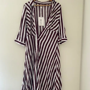 Klänning  - En lång klänning som är vit och typ marinröd. Helt ny storle L