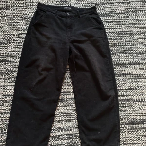 Svarta courdoroy byxor baggy - Säljer nu mina svarta courdoroy byxor  Gott skick rätt så loose fit. Lite heelbite på de men annars perfekt skick.  Köpta nya för 800. Hör av er om ni har frågor eller vill ha fler bilder.