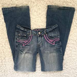 Coola låga utsvängda crazy age jeans med rosa detaljer! Ser ingen storlek men uppskattar xs/s. Midjemåttet är 36 cm tvärsöver och innebenslängden är 81 cm - jag är 166 cm 🩷 Något slitna vilket syns t ex vid benslutet på bild 1.