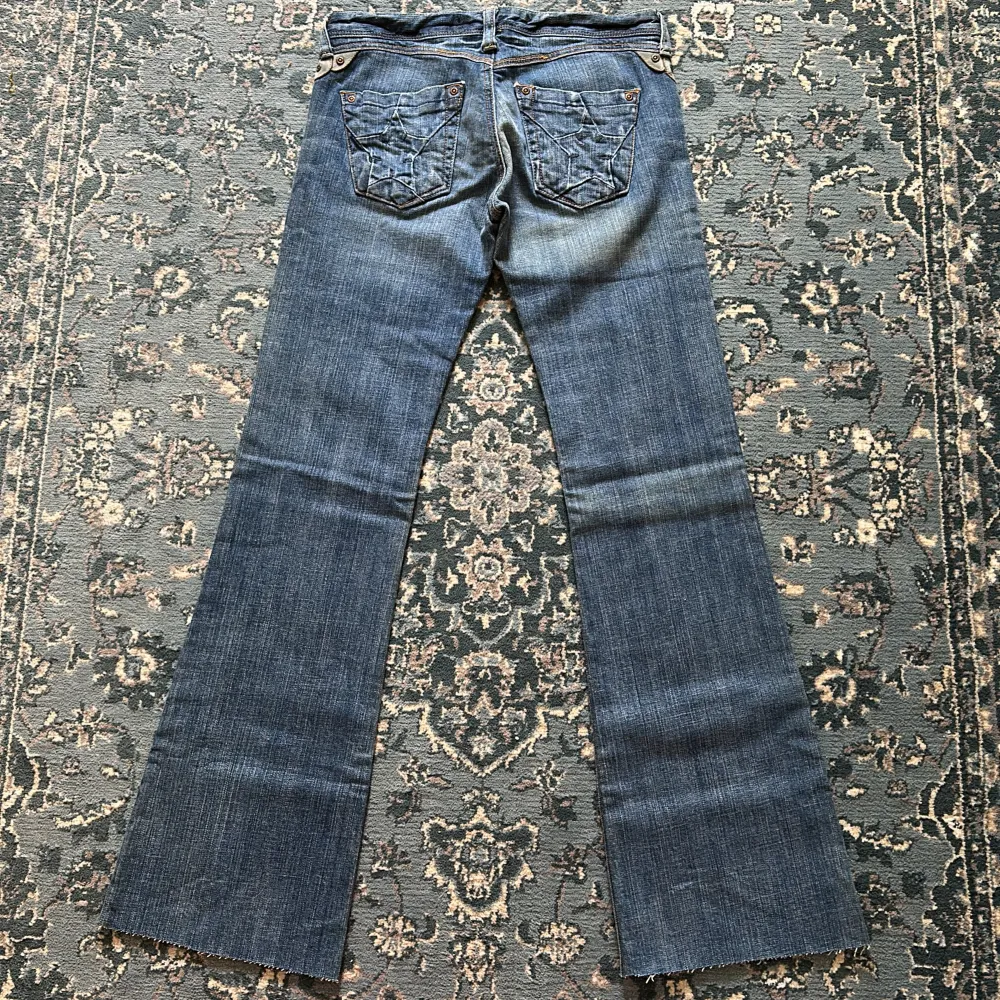 Säljer nu mina älskade vintage low rise bootcutjeans med skitsnygga stjärnor på fickorna vilket gör hela jeansen 🤩 Från 2000-talet! OBS; Jeansen är avklippta längst ner. Midjemåttet tvärsöver: 37 cm. Innerbenslängd: 80 cm. ⭐️💘. Jeans & Byxor.
