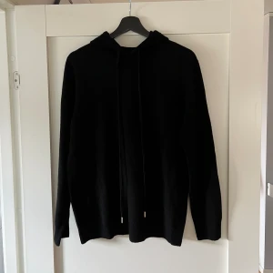Merino Hoodie - En svart hoodie i 100% merinoull. Inte använd alls och i superbra skick. Nypris ca 1300. PRIS ÄR DISKUTERBART!