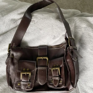 Roxanne väska - Säljer denna Roxanne axelväska som är köpt på en secondhand! Den är i bra skick förutom att den är sliten på insidan av bandet längst upp, men det syns knappt från utsidan! Den är snygg känns som bra kvalitet! Skriv vid frågor!