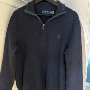 Polo Ralph Lauren tröja - Hej! Säljer en Ralph lauren half zip i färgen marinblå. Skicket är väldigt bra, tröjan har inga defekter så som hål eller fläckar. Nypris på dessa ligger kring 2200kr, priset är inte hugget i sten och går att diskutera. Skick 8/10 nästintill ny.