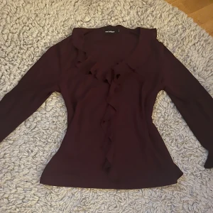 Vinröd blus med volangdetaljer - Vinröd blus med volangdetaljer. Volang vid slutet av ärmarna och runt halsen.🍇👚Färgen syns bäst på tredje bilden. 