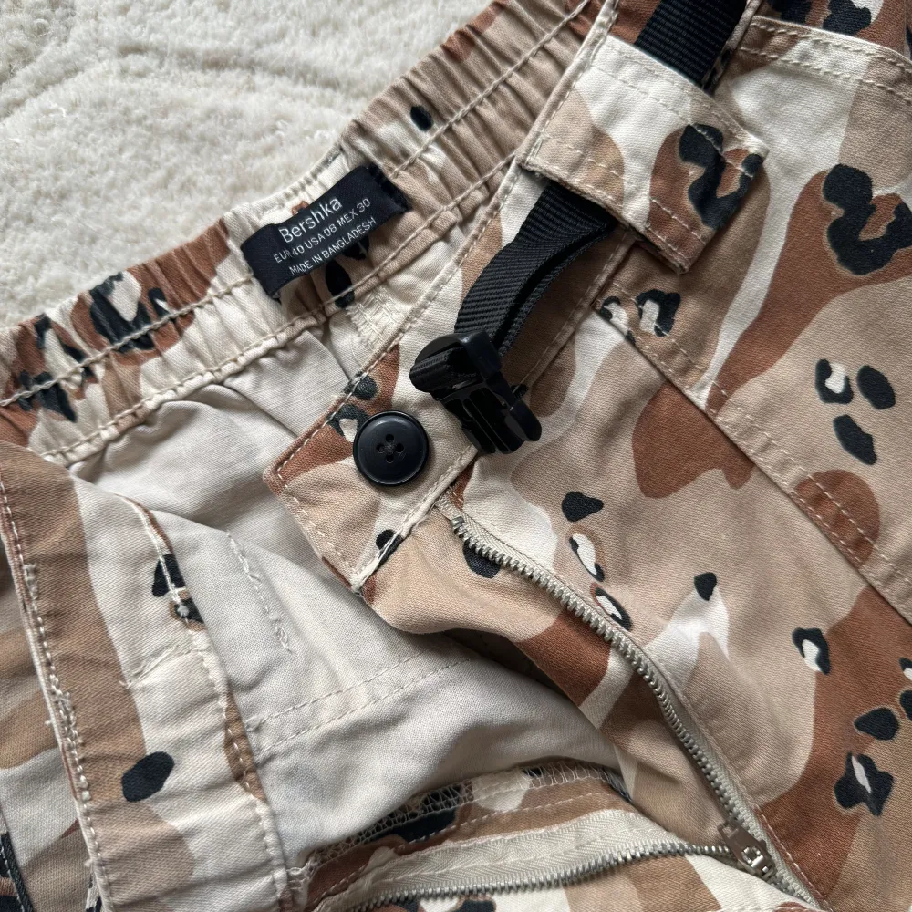 Brunbeiga kamouflage och cargobyxor, med djupa fickor på sidan och justerbar midja.  Som nya, använda en gång Storlek 40 men passar 38. Jeans & Byxor.