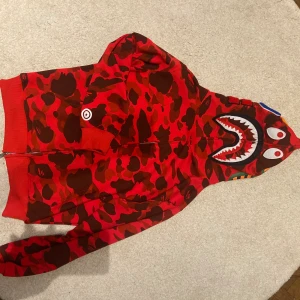 Bape Hoodie  - Röd bape hoodie, lite använd skriv vid frågor, de står storlek L men passar som M eller oversized S 